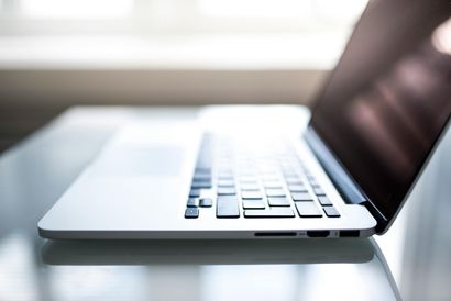 Laptop computer, angled view, open on a glass table.