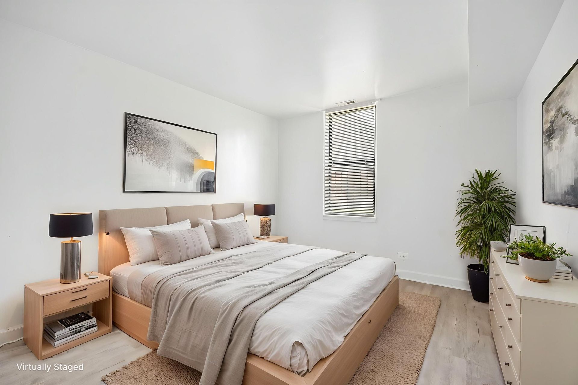 Bright minimalist bedroom with a bed, bedside lamp, dresser, and window blinds