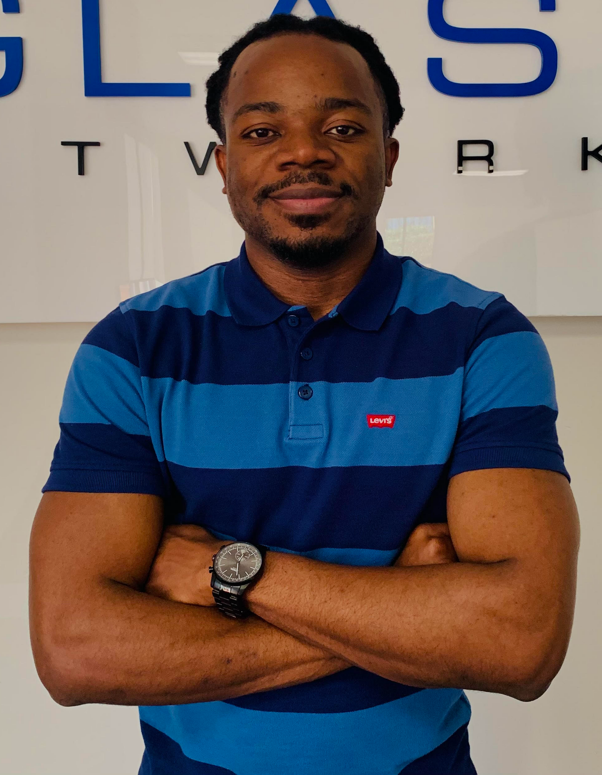 A man in a blue and black striped shirt with his arms crossed