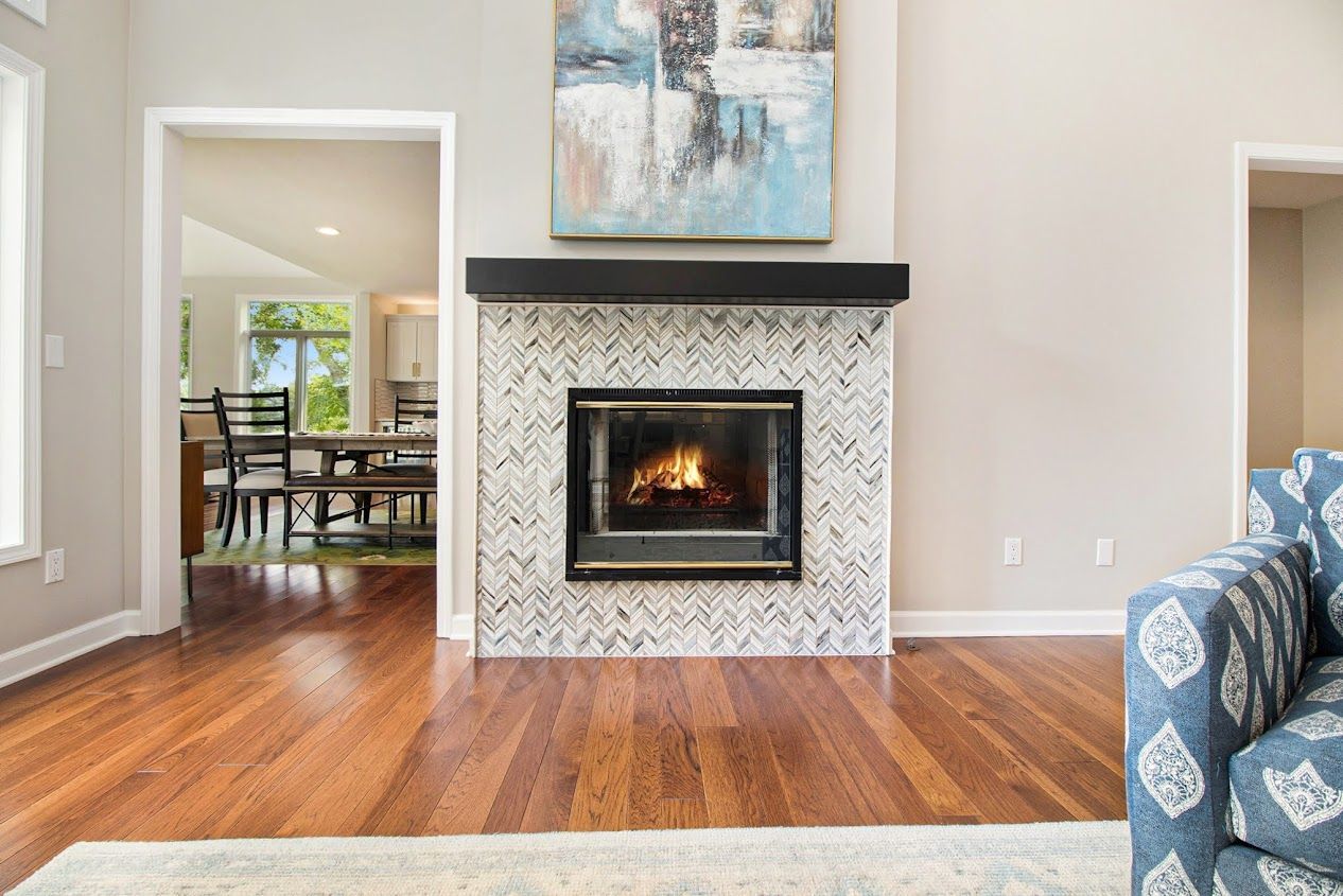 Bright living room with a marble fireplace, hardwood floors, and open doorway to a dining area.