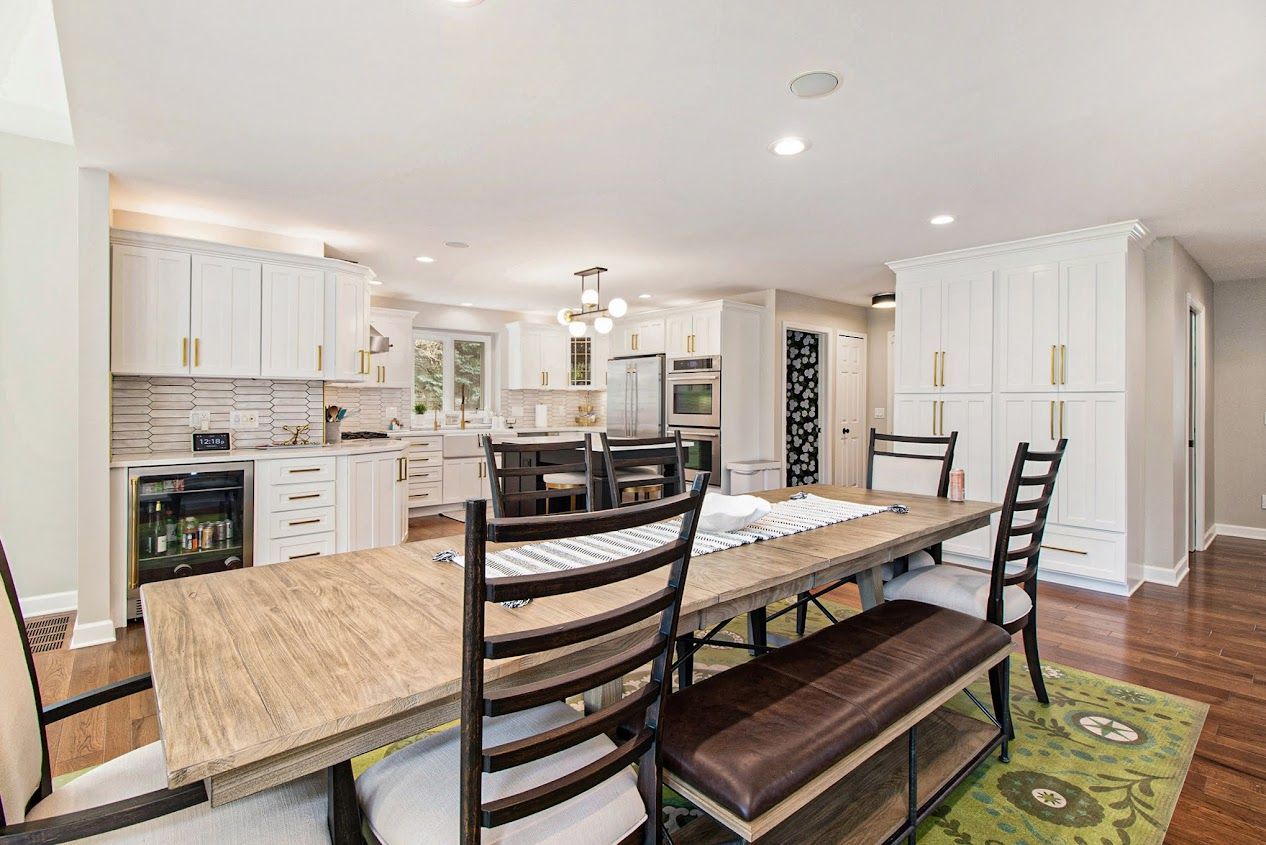 Bright kitchen and dining area with white cabinets, wood table, and bench seating