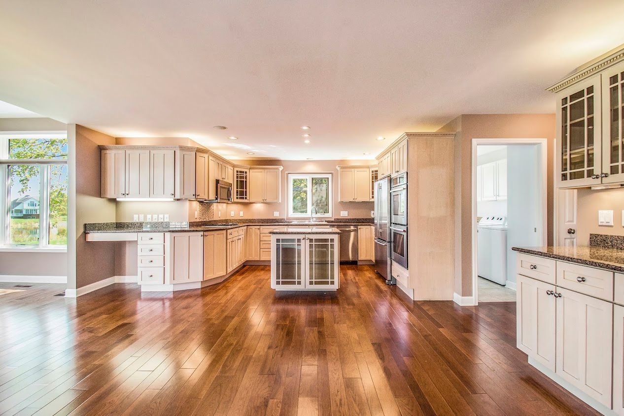 Bright open kitchen with white cabinets, hardwood floors, and a large island in a sunlit home interior