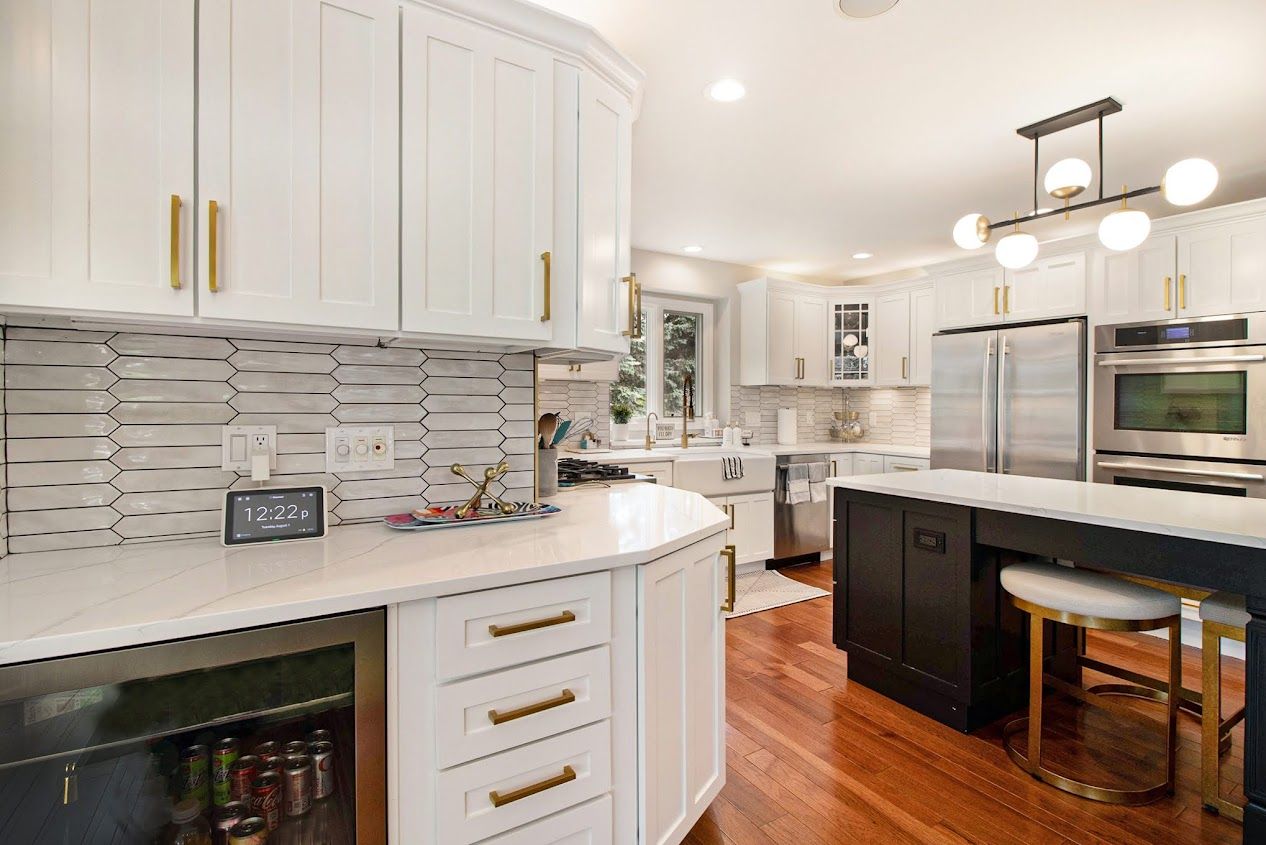 Bright modern kitchen with white cabinets, dark island, stainless appliances, and hardwood floors