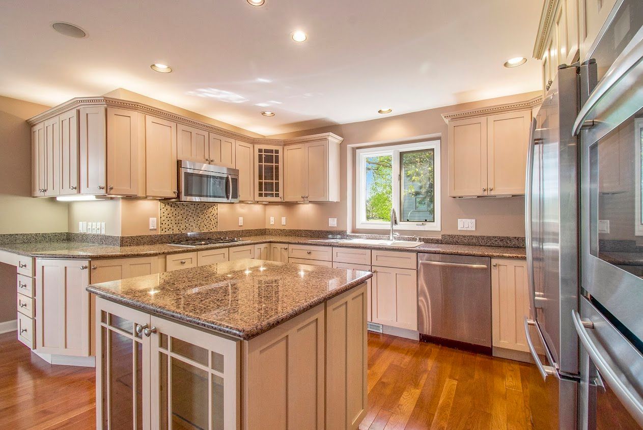 Bright modern kitchen with wood cabinets, granite island, and stainless steel appliances