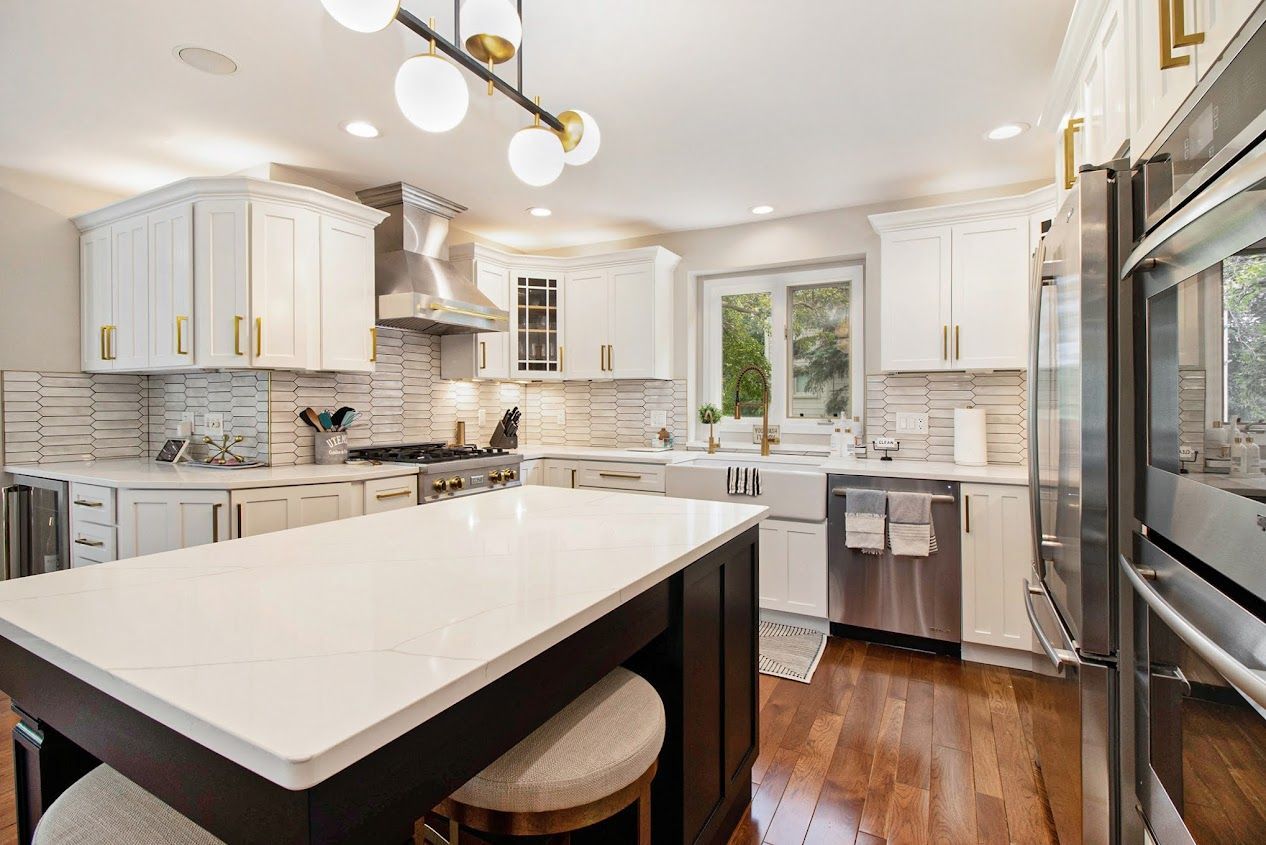 Bright modern kitchen with white cabinets, marble island, stainless appliances, and hardwood floors