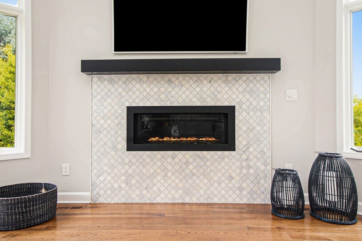 Modern living room with a wall-mounted TV, black fireplace, patterned tile surround, and wicker baskets.