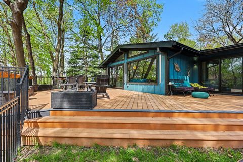 Wooden deck with teal house, patio seating, and trees in a sunny backyard