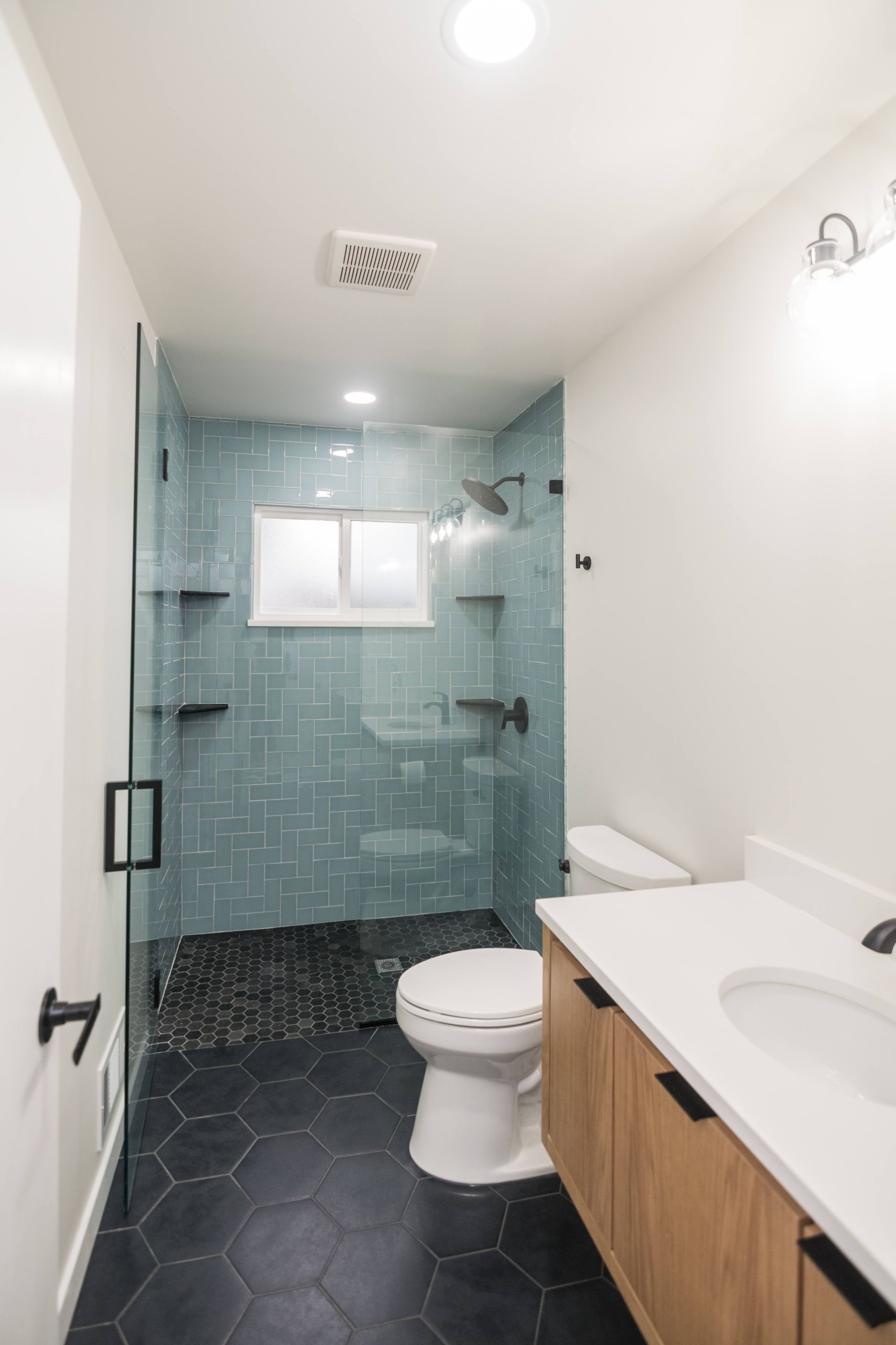 Modern bathroom with glass shower, white toilet, and wood vanity with sink