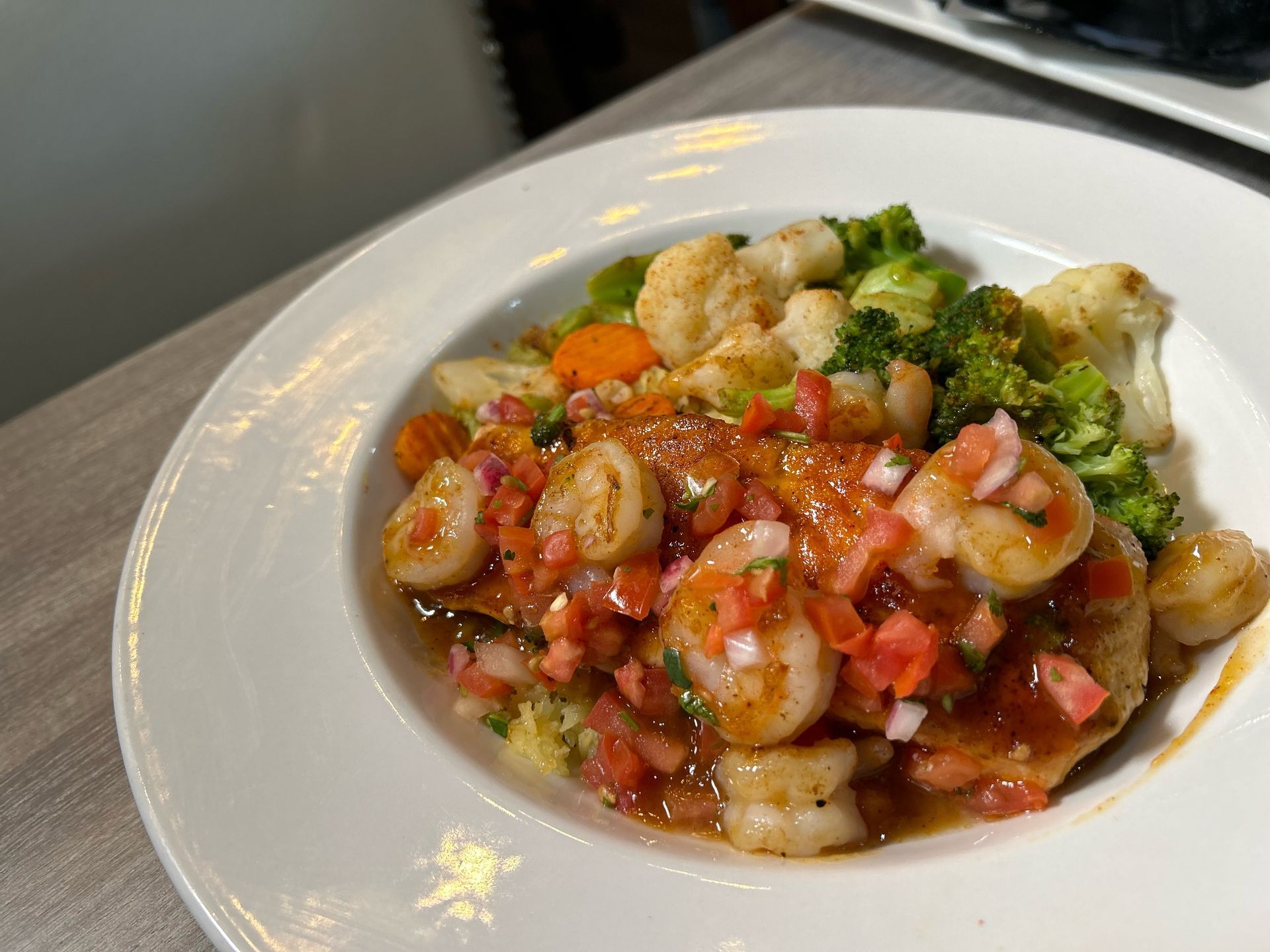 A white plate topped with shrimp and vegetables on a table.