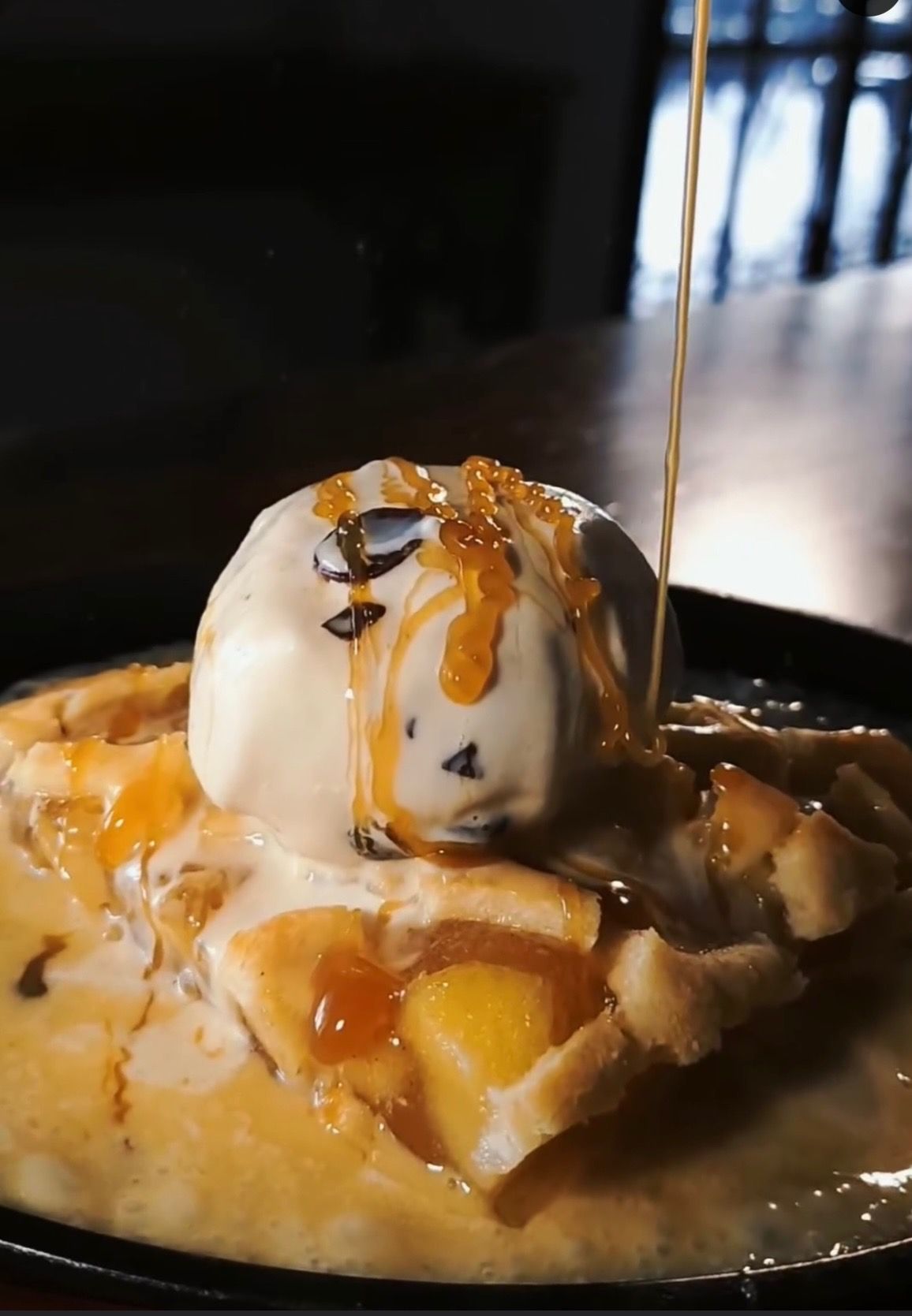 A pie with a scoop of ice cream and syrup on top