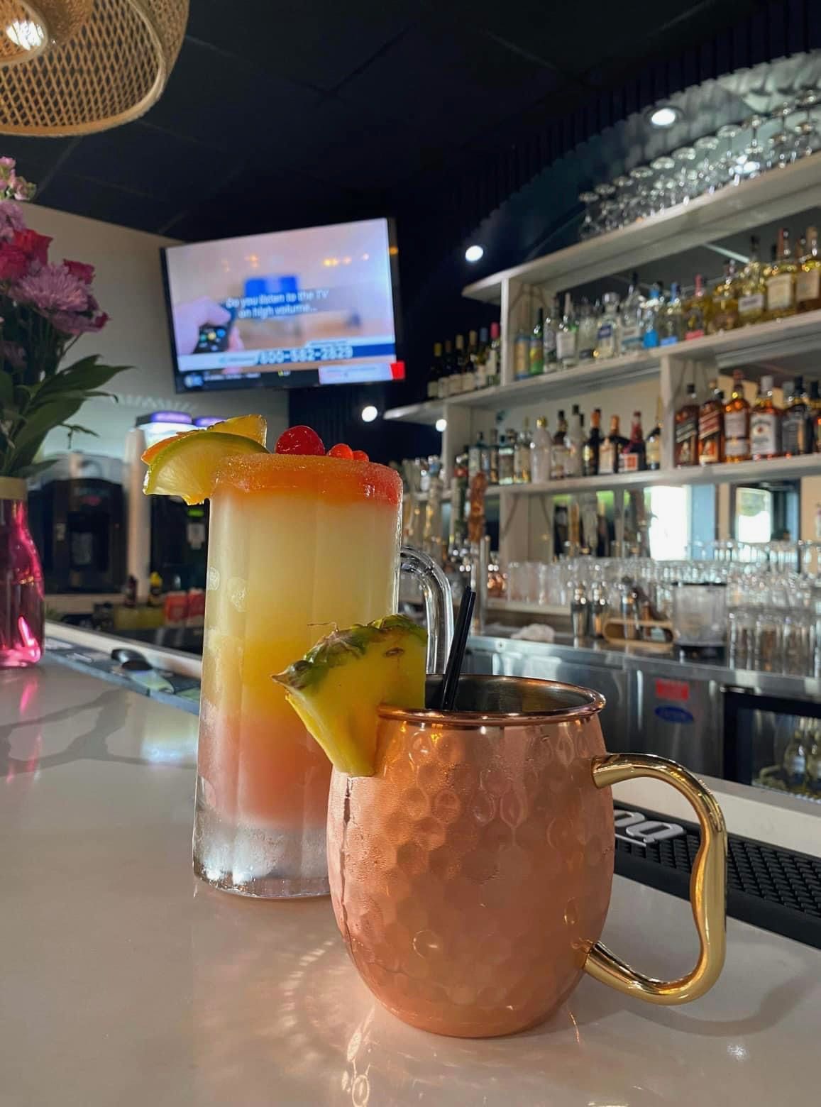 Two drinks are sitting on a bar in a restaurant.