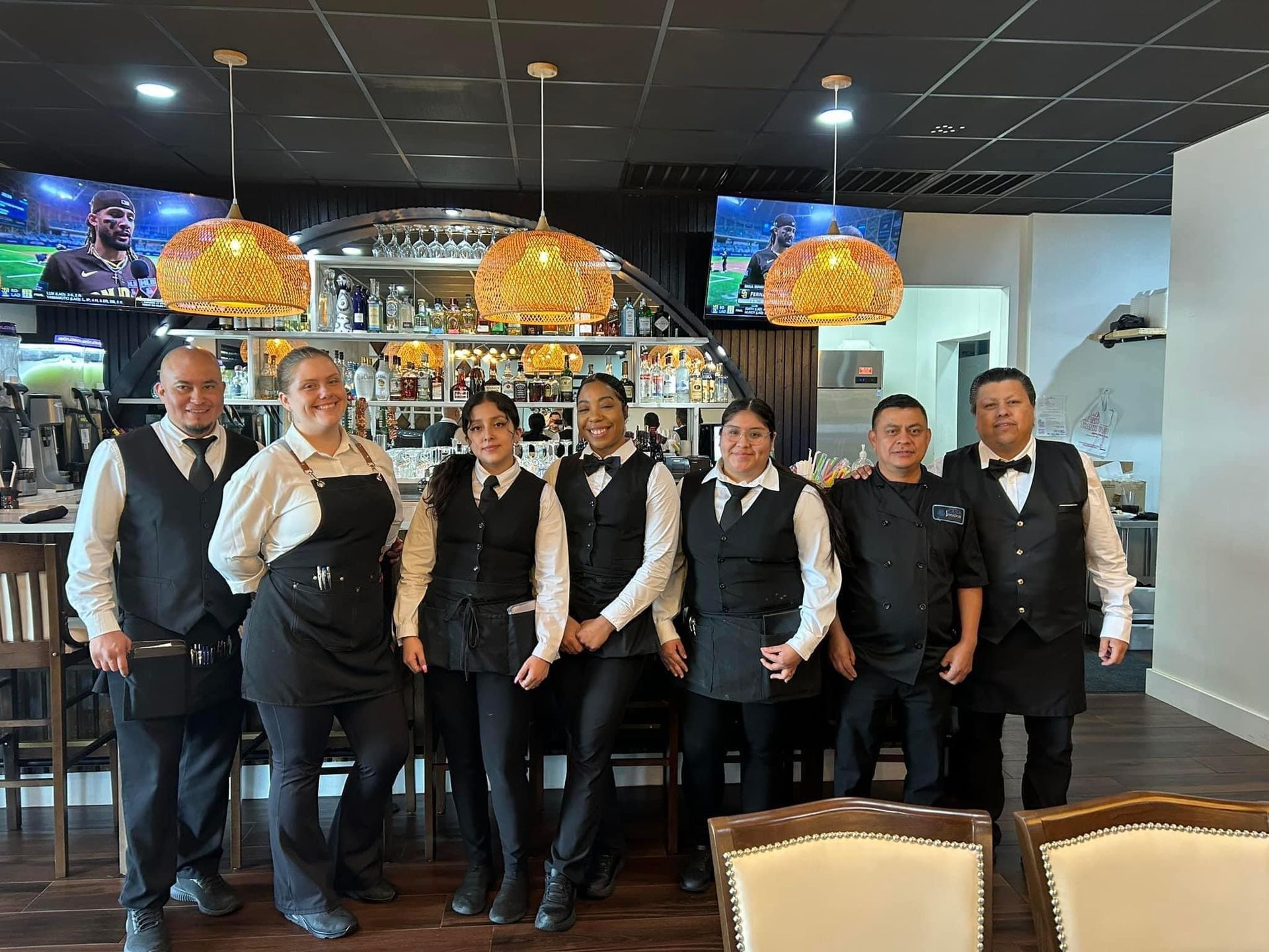 A group of waiters and waitresses are posing for a picture in a restaurant.