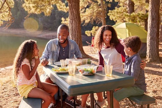 A family is sitting at a picnic table near a lake.