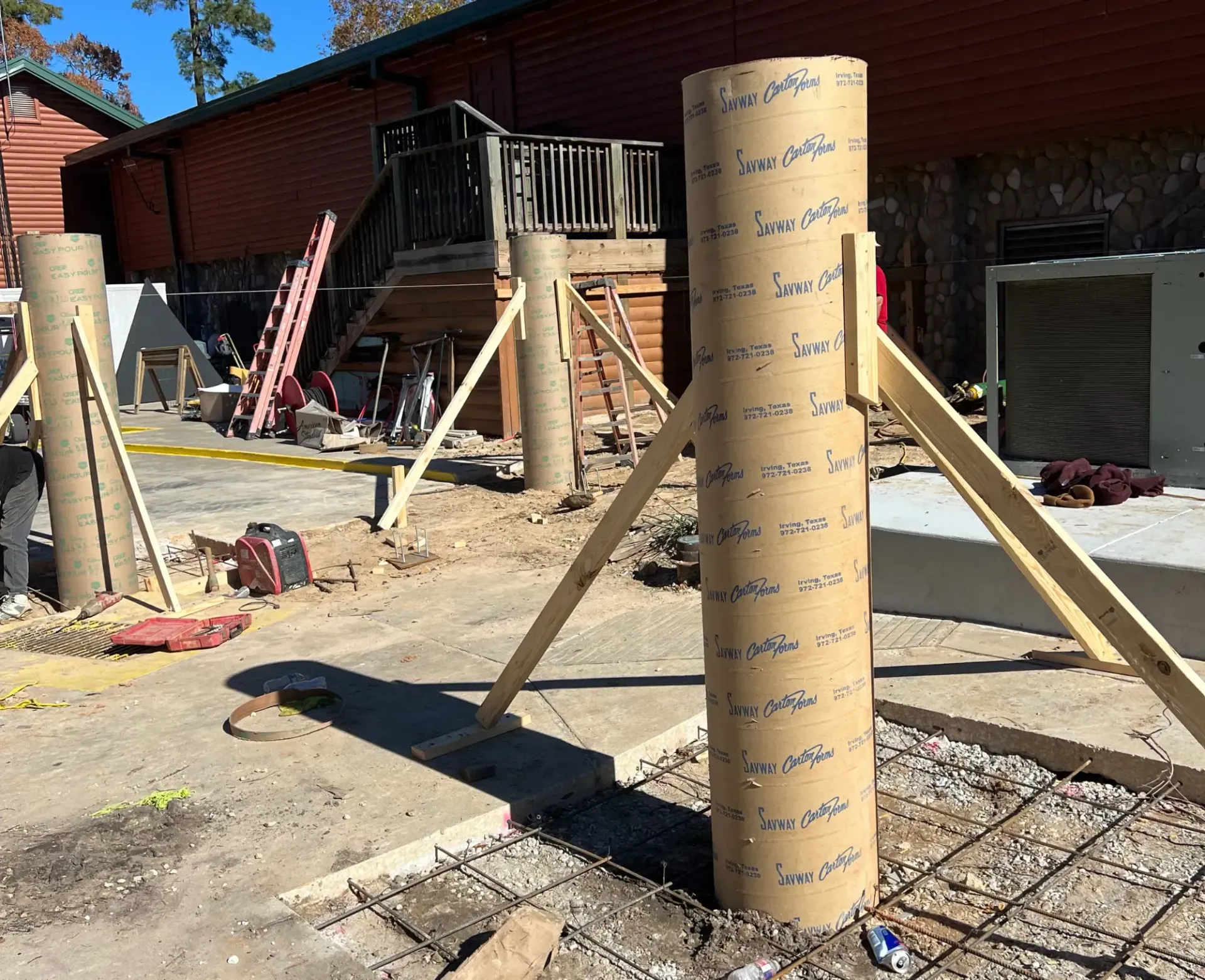 Wrapped wooden post with braces on a construction site outside a red building