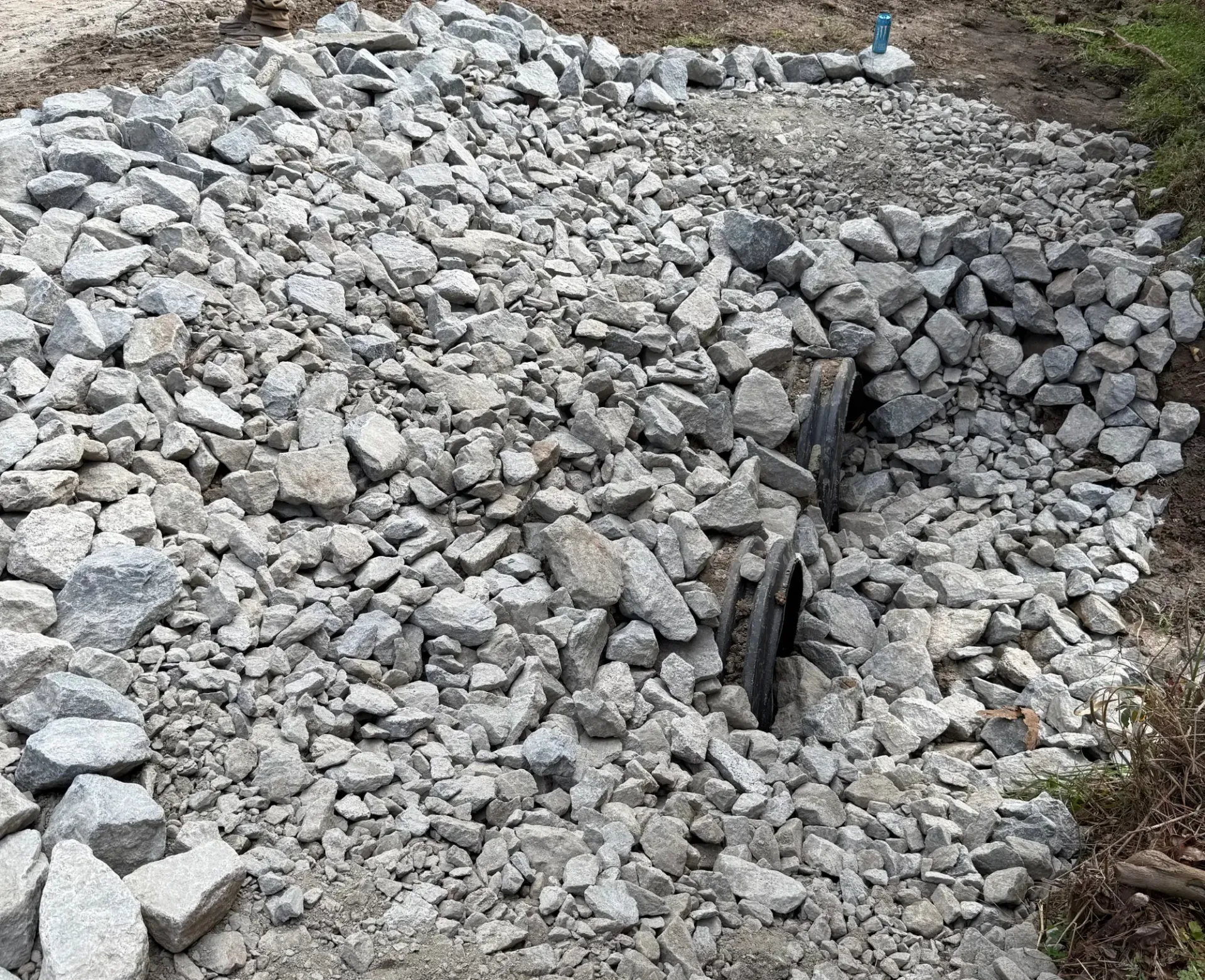Pile of gray rocks and rubble with a narrow trench or gap in the center outdoors
