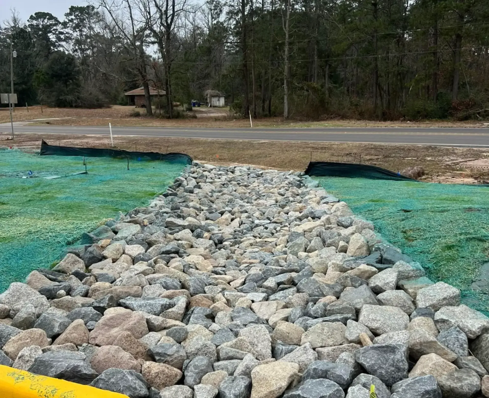 Rock-filled drainage channel leading across a dirt area at a construction site