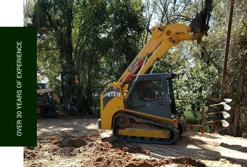Yellow mini excavator on a dirt path in a wooded area, with a green vertical banner on the left.