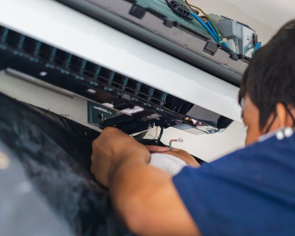 A man in a blue shirt is working on an air conditioner.