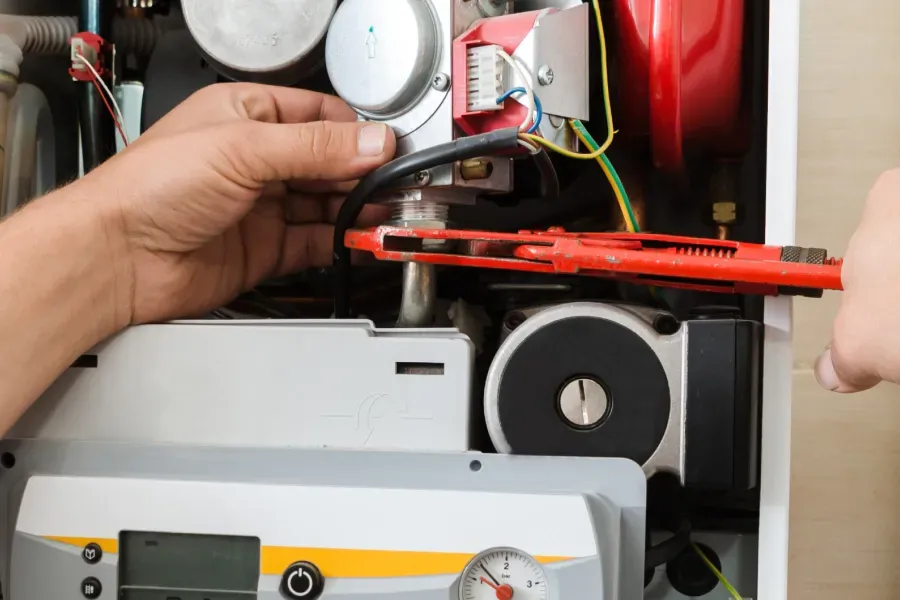 A person is fixing a boiler with a wrench.