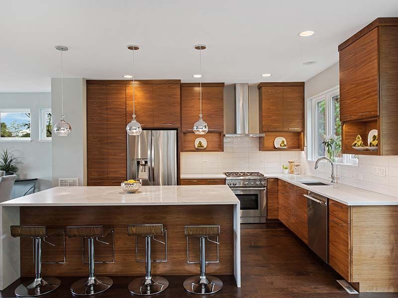 Modern kitchen with wood cabinets, stainless steel appliances, and white countertops.