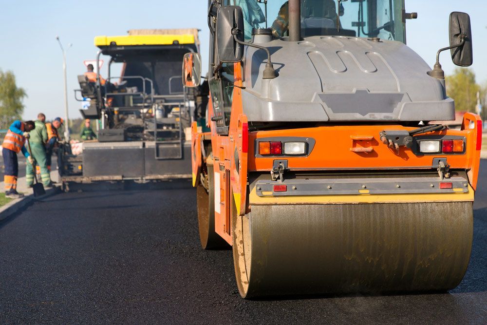 A Roller Is Being Used To Spread Asphalt On A Road — Absolute Dingo Services in White Rock, QLD