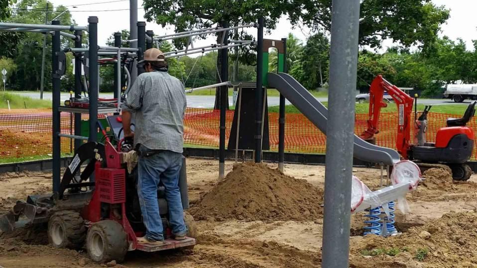 A Man Is Working On A Playground With A Mini Excavator — Absolute Dingo Services in White Rock, QLD