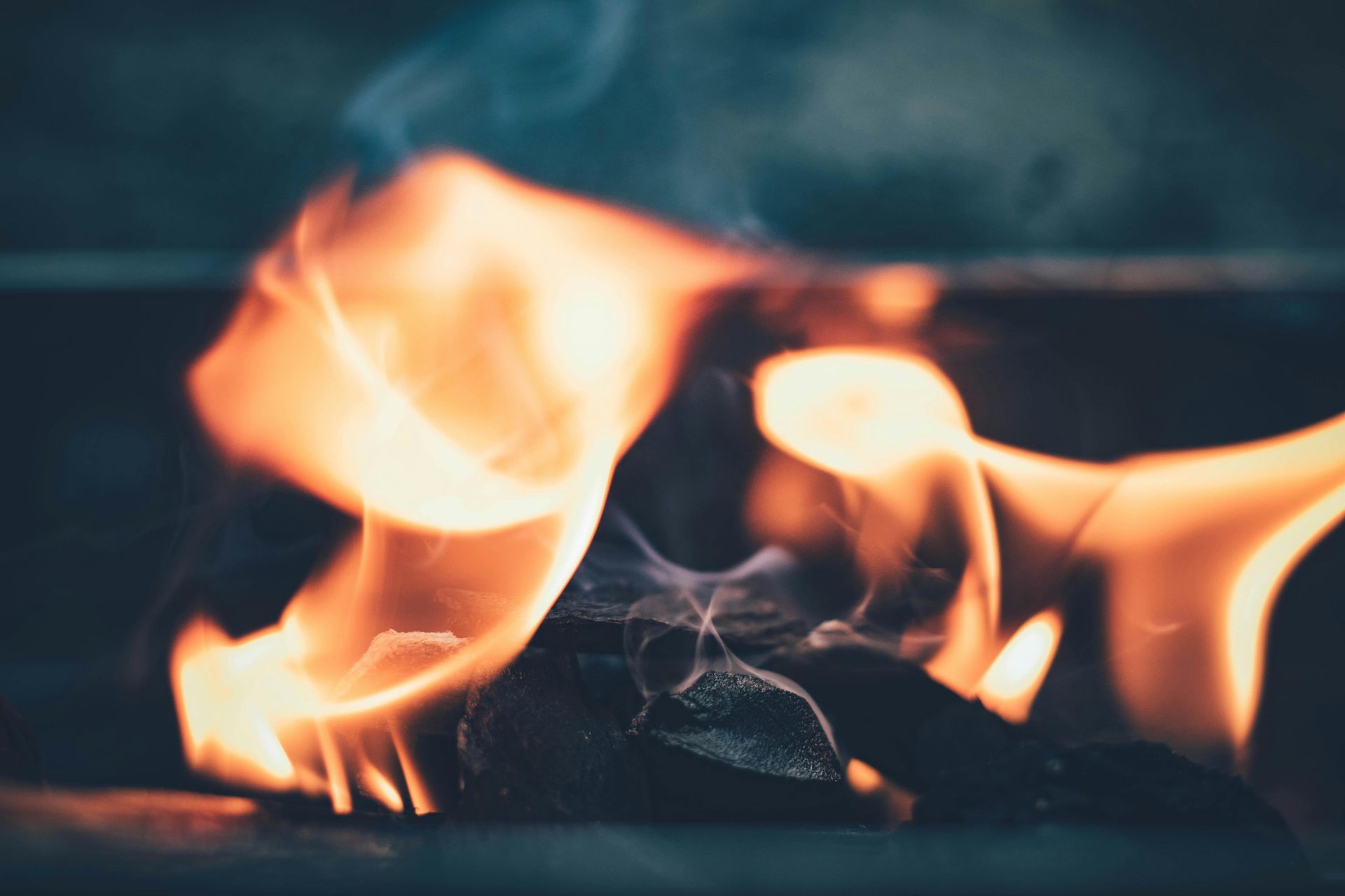 Flames of orange and yellow fire rising from smoldering embers against a dark background.