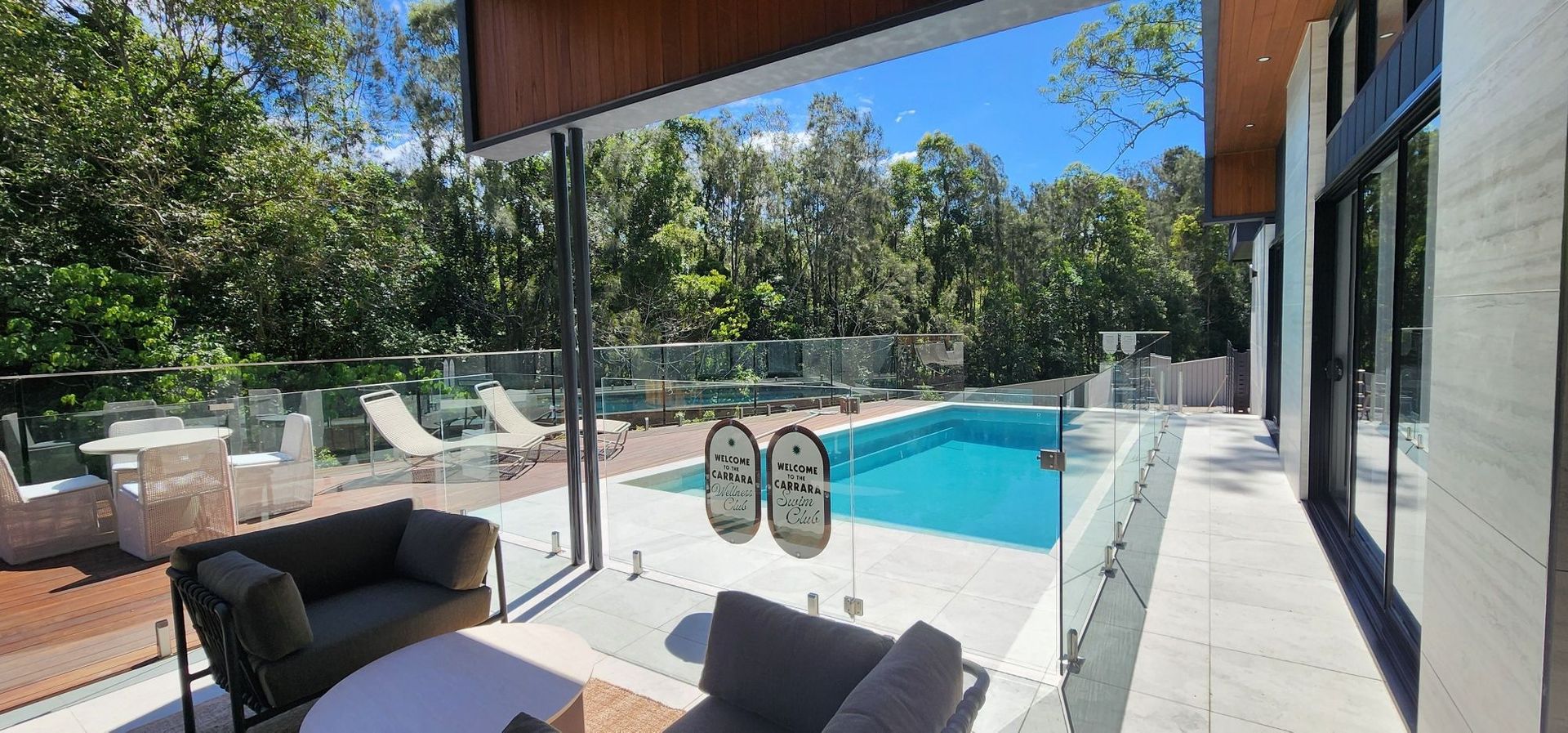 Patio view of a bright backyard pool with lounge chairs and glass doors
