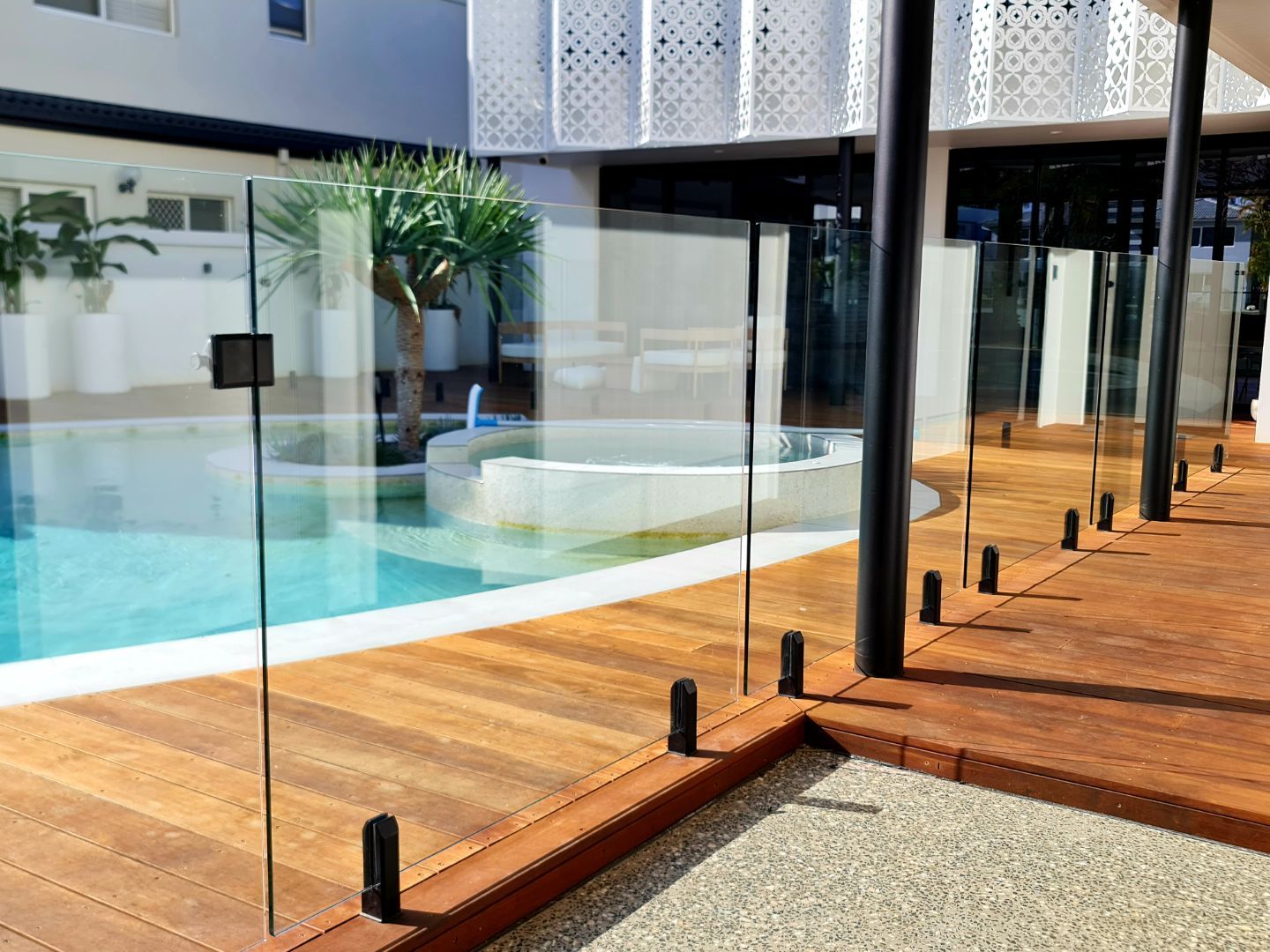 Pool area with glass fence and wooden deck.