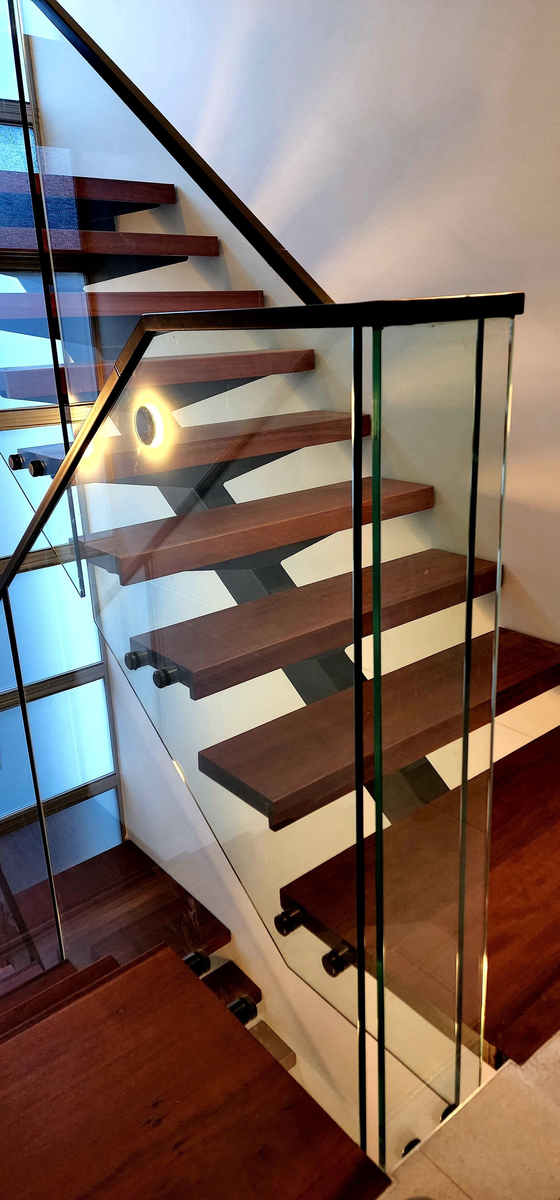 Modern wooden staircase with glass railing.