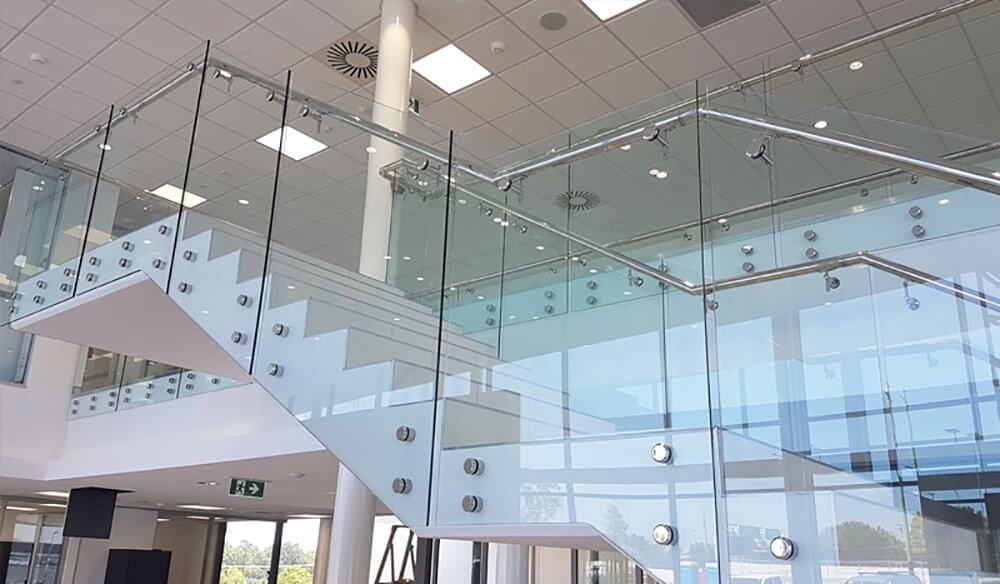 Modern staircase with glass panels and white steps, inside a building.