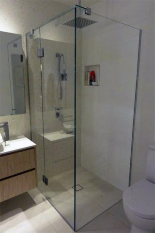 Modern bathroom with glass shower enclosure, white walls, and wooden vanity.