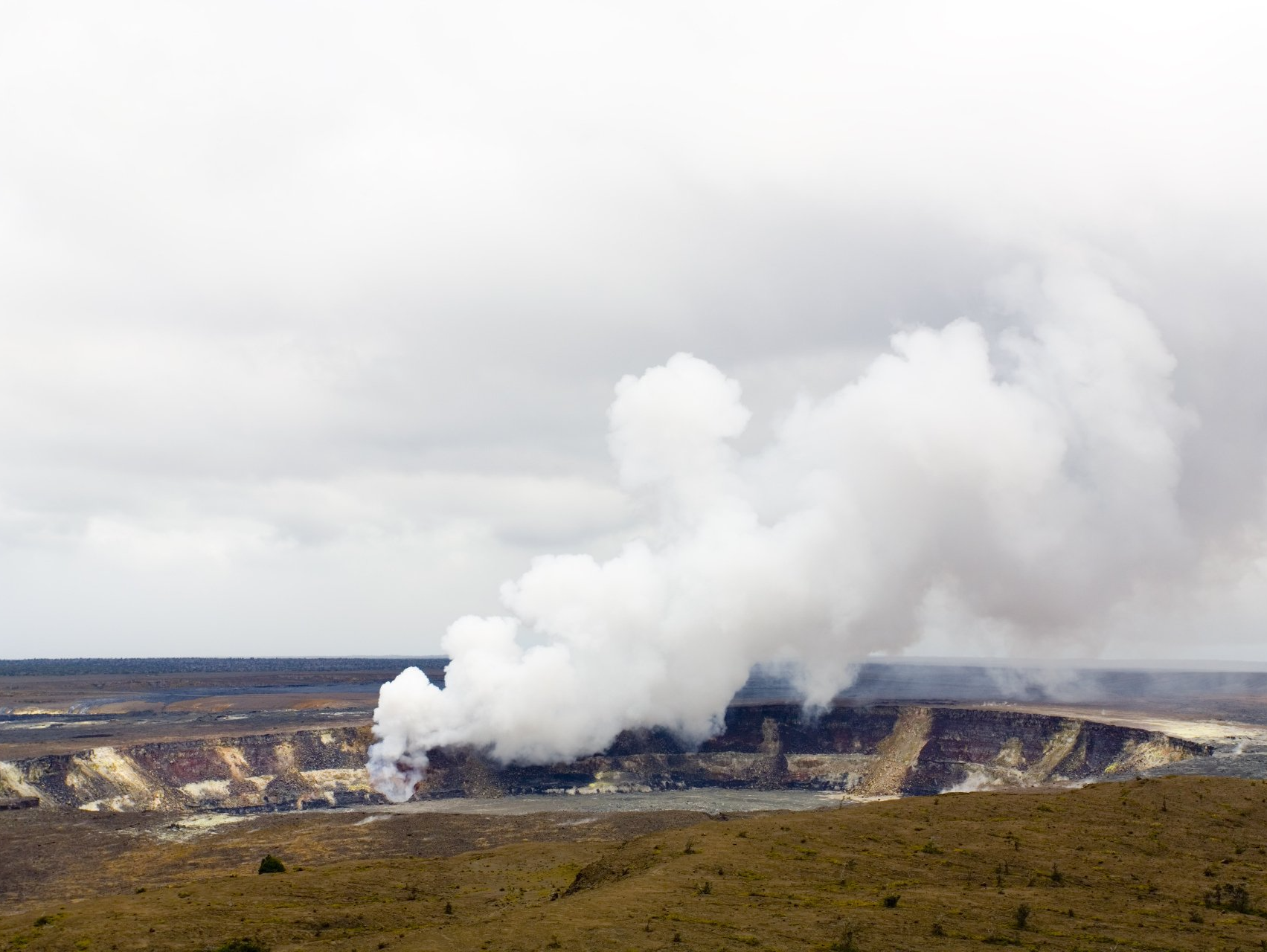 Steam billowing from an industrial site in a barren landscape under a cloudy sky