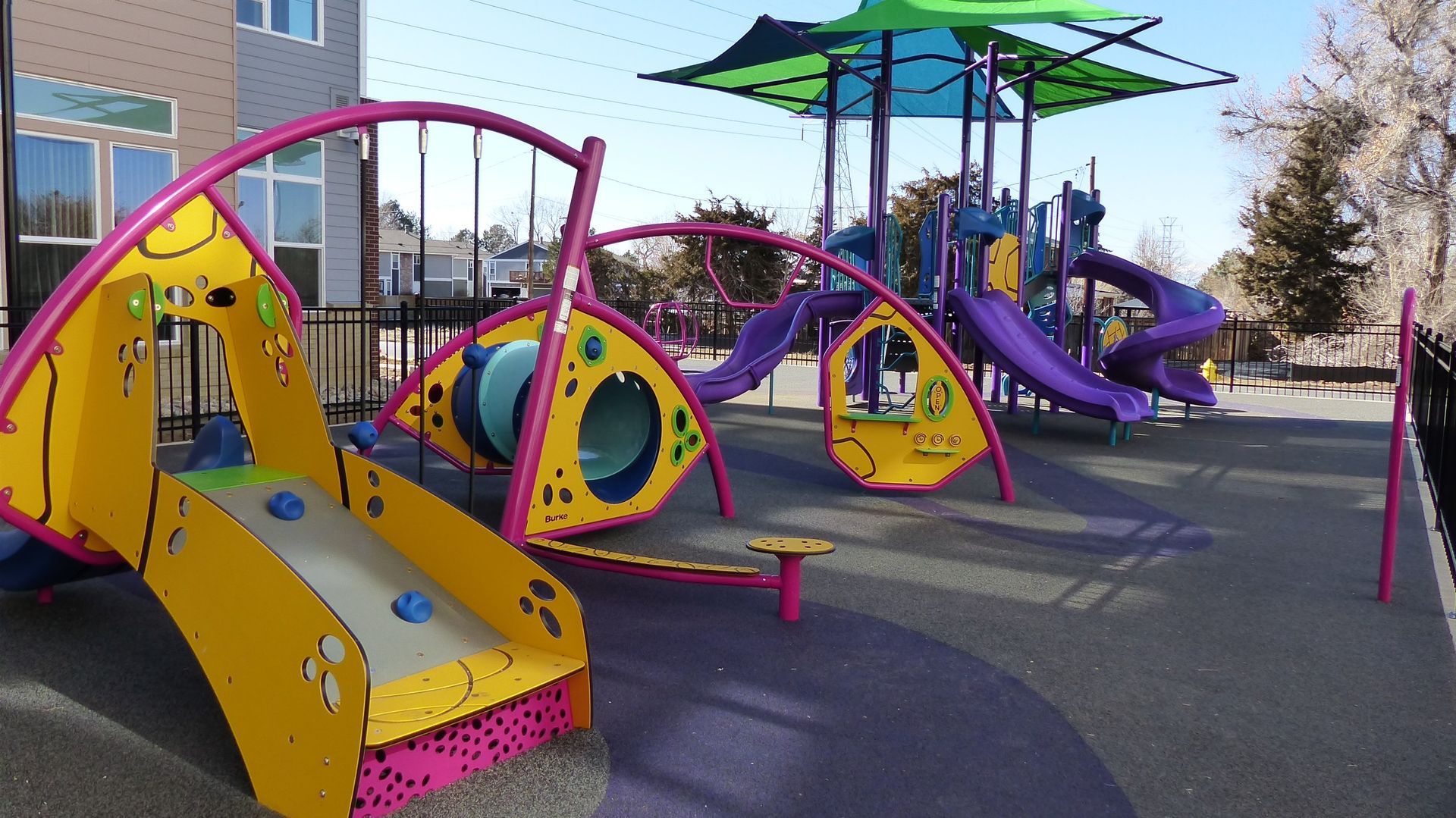 Colorful playground with slides, climbing tunnels, and shade umbrellas on a sunny day