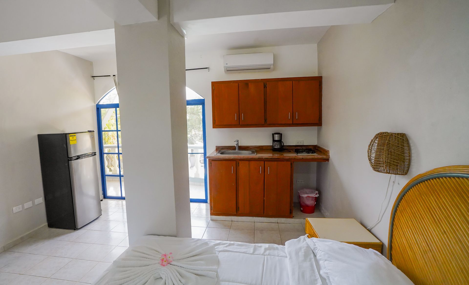 Small studio room with bed, kitchenette, refrigerator, and sliding glass door.