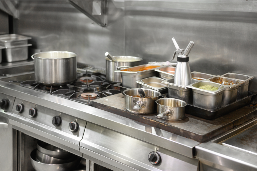 A kitchen with stainless steel appliances and pots and pans on the stove.