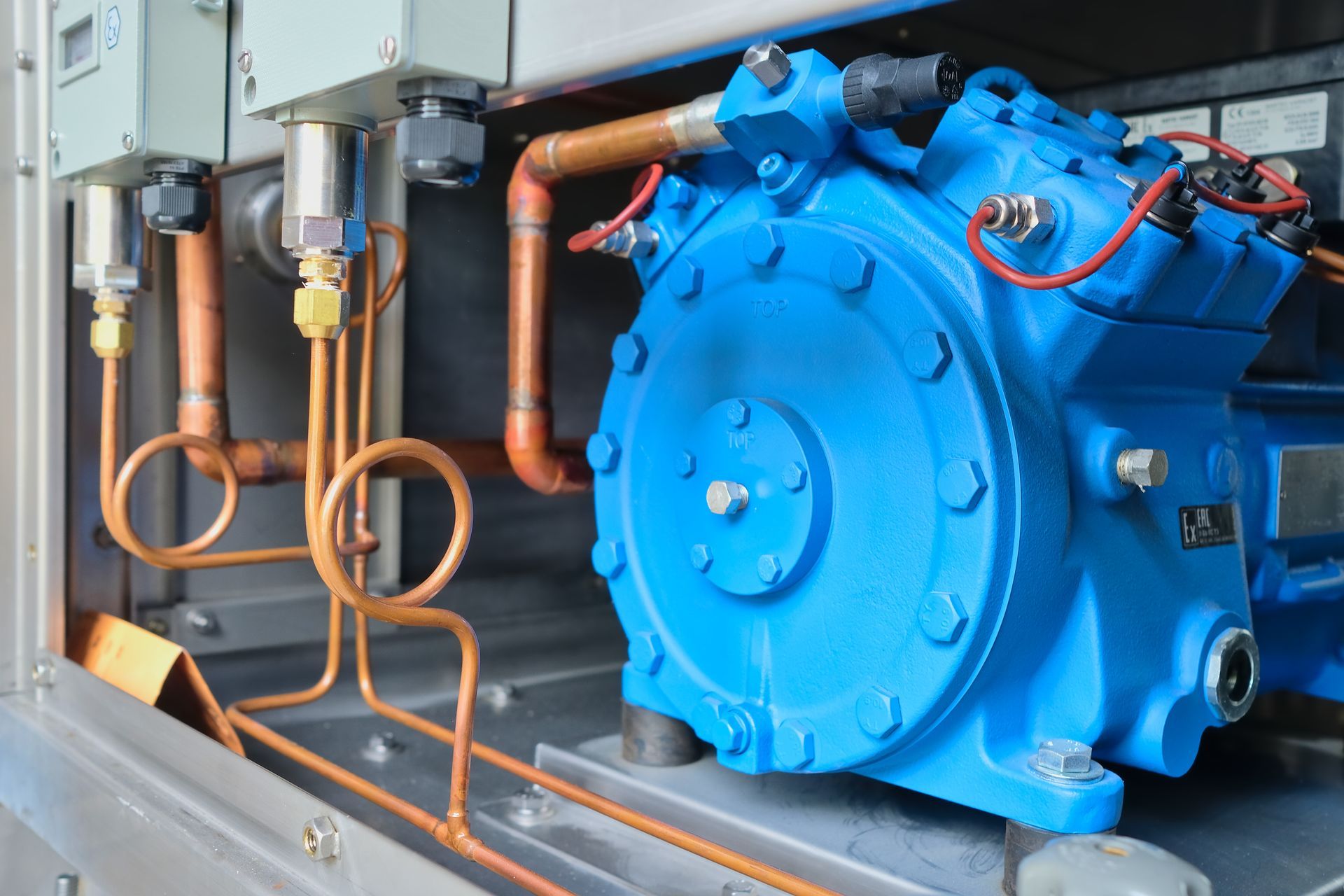 Blue air compressor with copper pipes in an industrial setting.
