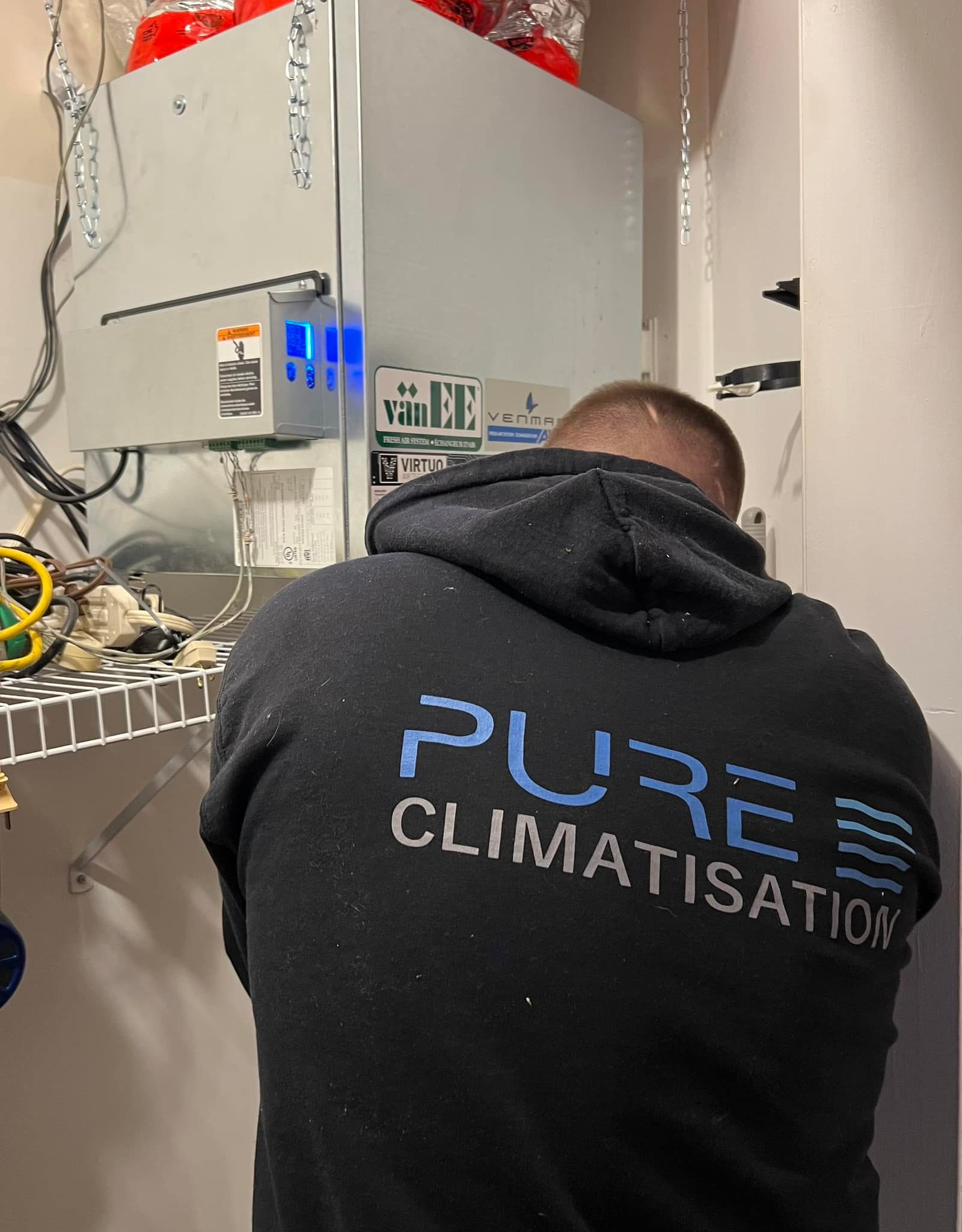 Un homme portant un sweat à capuche sur lequel est écrit « pure climatisation »
