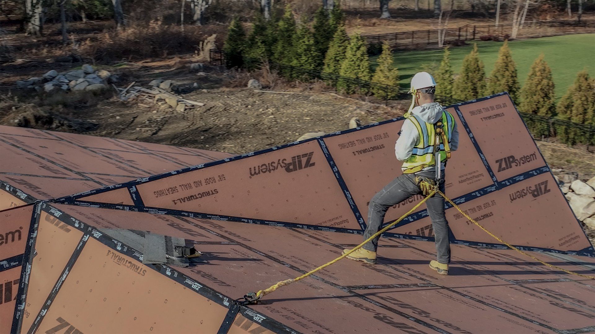 Roofer in safety harness on a roof with ZIP System sheathing.
