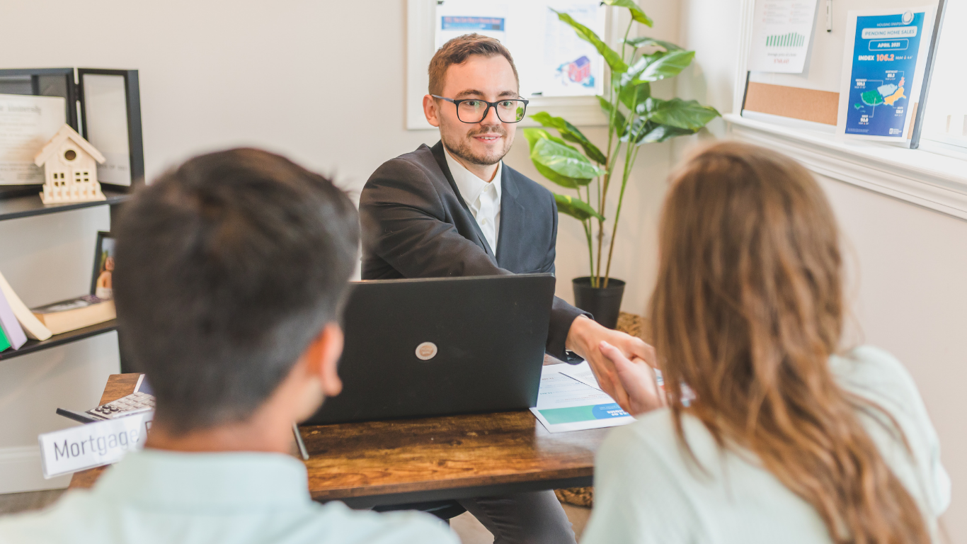 Counselor speaking with two clients across a desk in a bright office