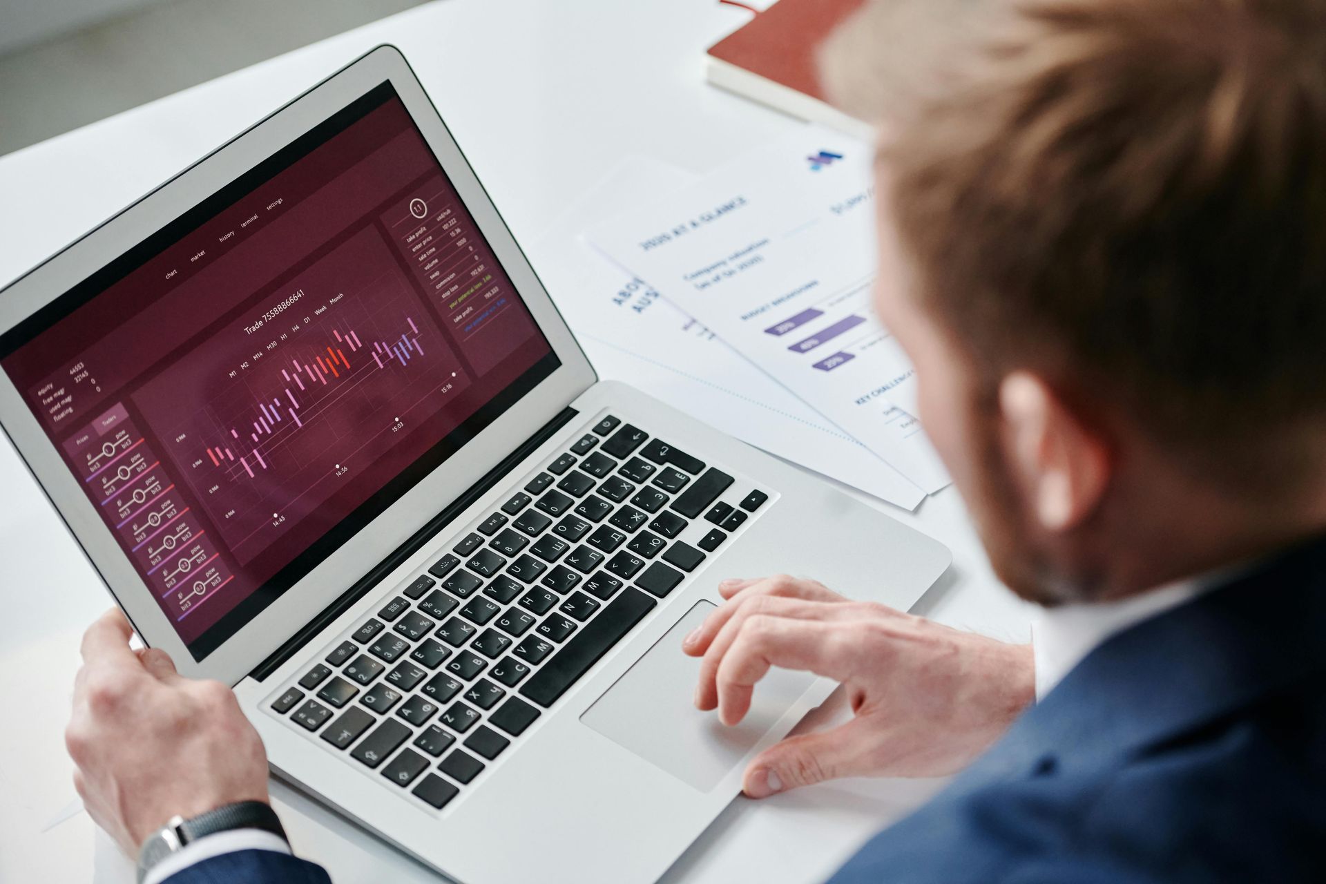 A man is using a laptop computer with a graph on the screen.