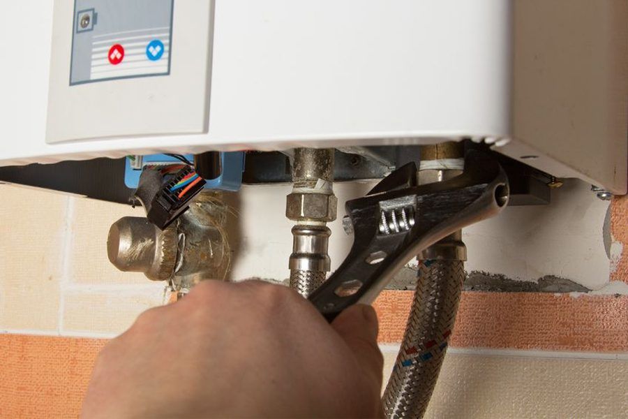 Hand Adjusting A Water Heater Pipe Connection With A Wrench — Huddo's Plumbing Service in Wallalong, NSW