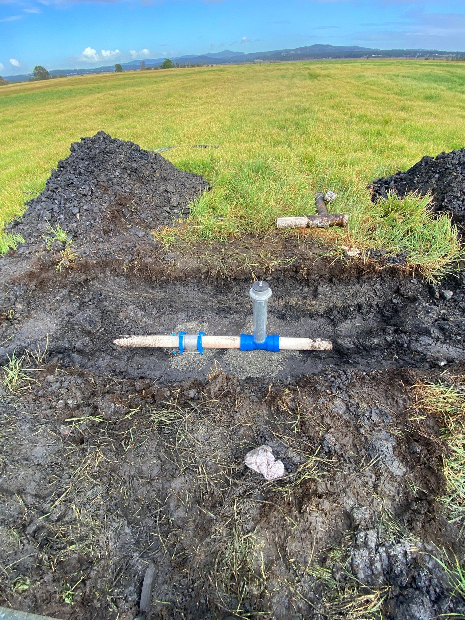 Broken Pipe in a Muddy Field, With Blackened Ground — Huddo's Plumbing Service in Newcastle, NSW