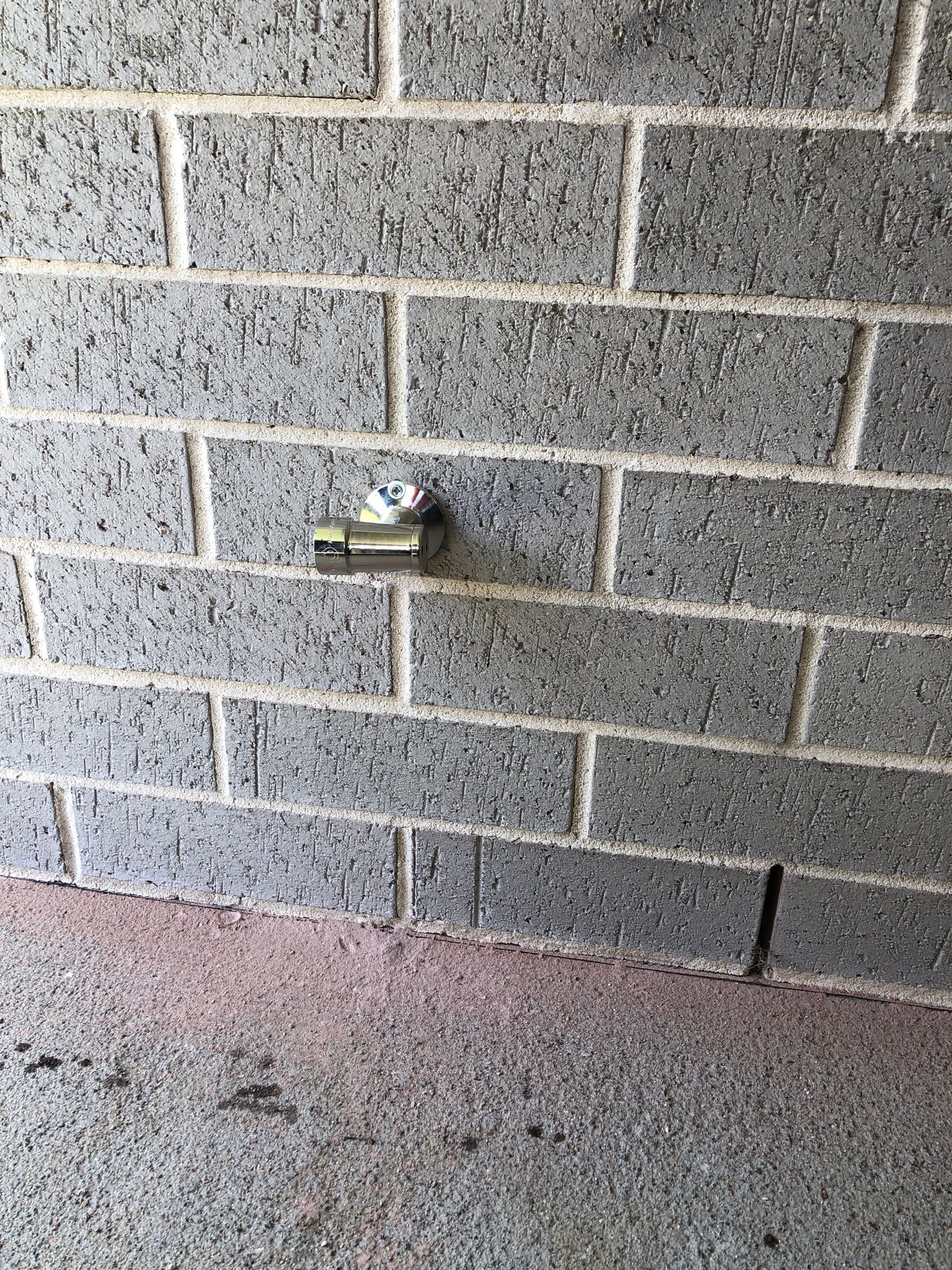 Concrete Block Wall With A Small Metal Fixture Mounted — Huddo's Plumbing Service in Wallalong, NSW