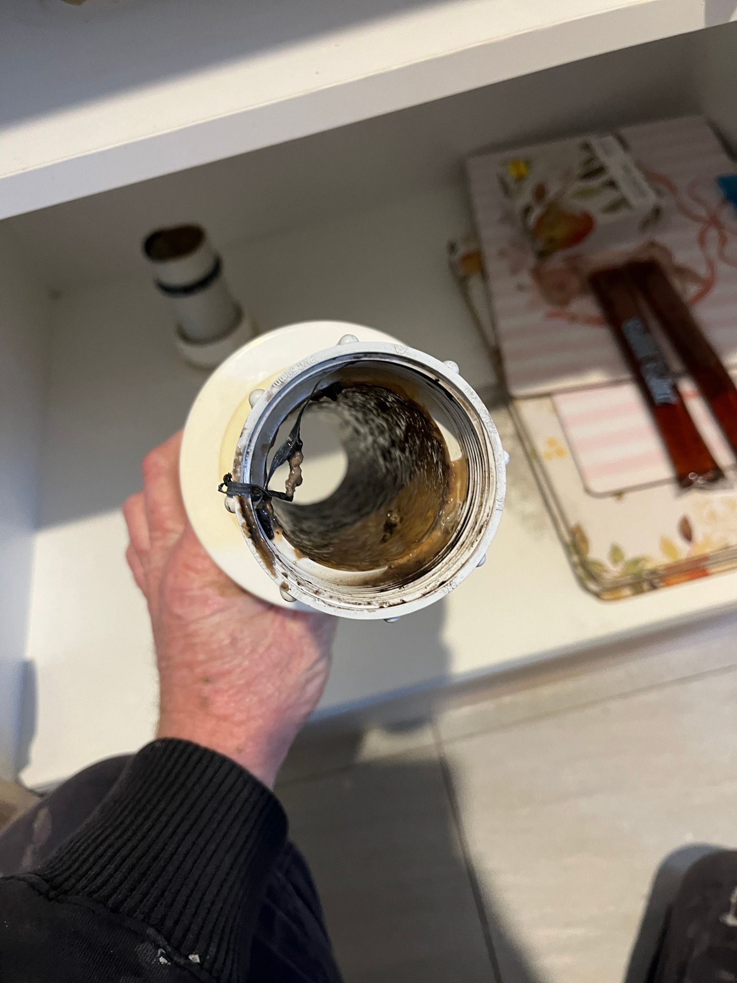 Hand Holding a White Pvc Pipe With Dark Buildup Inside — Huddo's Plumbing Service in Wallalong, NSW