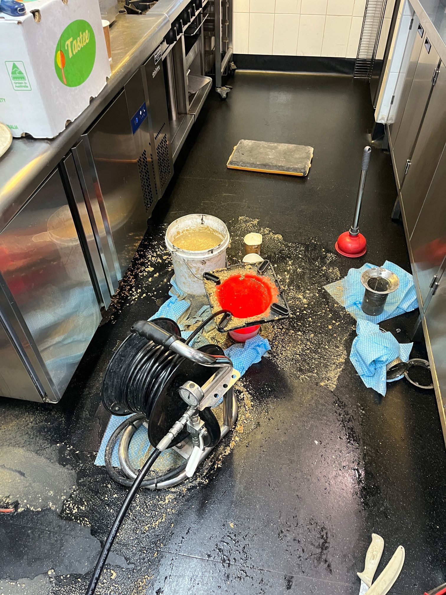 Spilled Liquids and Cleaning Supplies on a Wet Kitchen Floor — Huddo's Plumbing Service in Wallalong, NSW