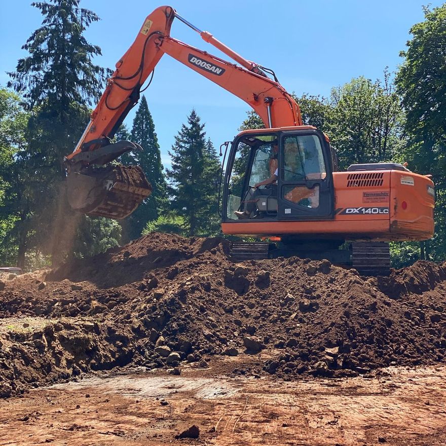 Orange excavator scooping dirt on a mound at a sunny outdoor construction site