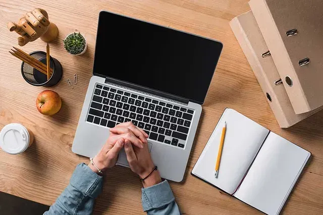 A person is sitting at a desk using a laptop computer.