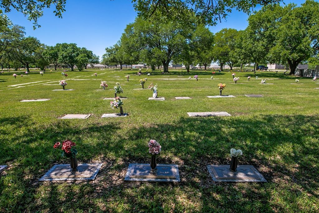 A cemetery filled with graves and flowers on a sunny day.