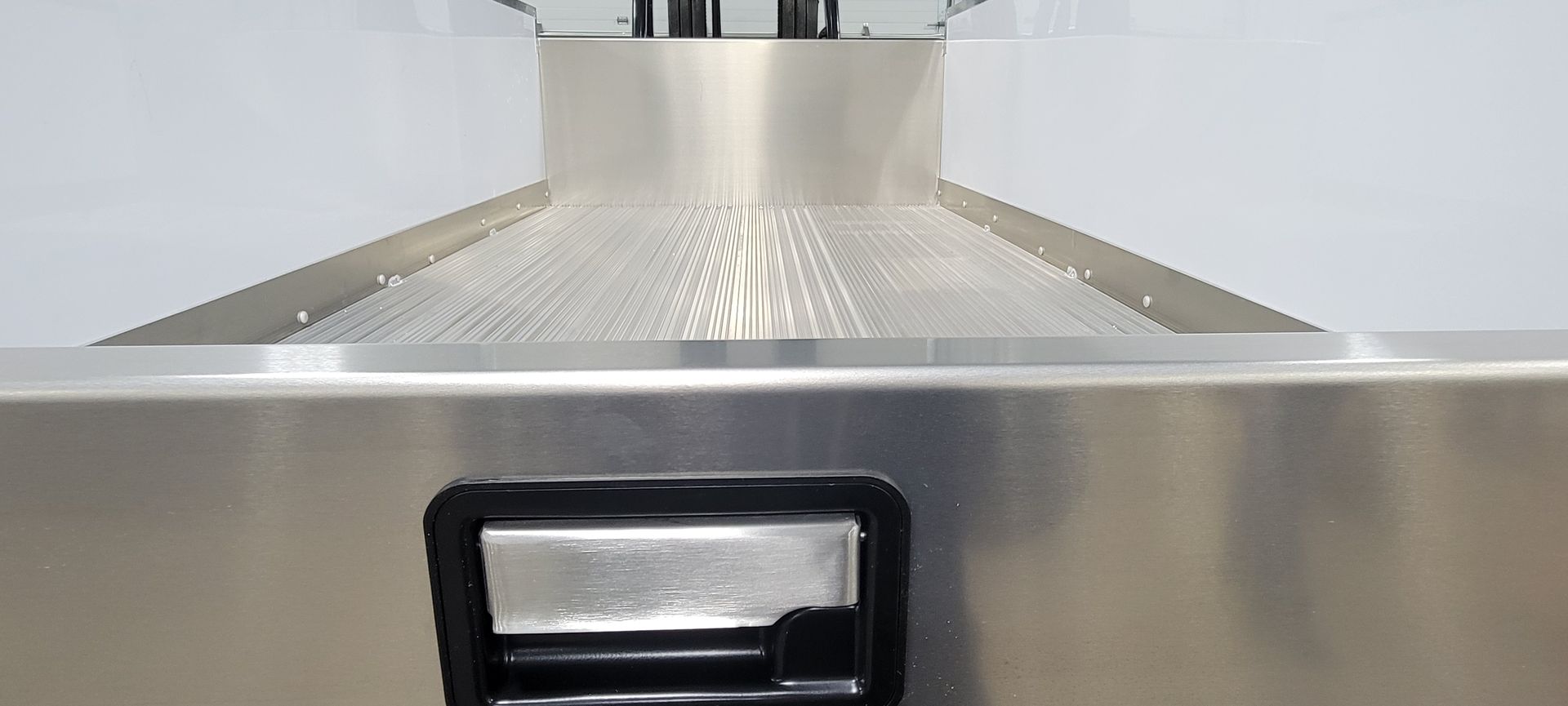 A close up of a stainless steel drawer with a black handle.